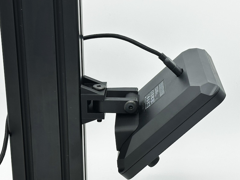 May include: A black camera monitor mounted on a black metal pole with a black cable connected to the back.