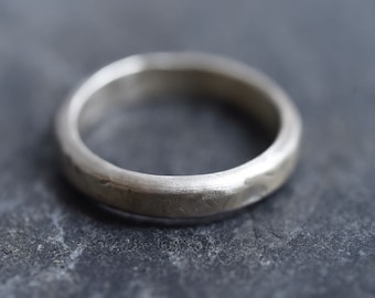 May include: A simple silver band ring with a hammered finish.