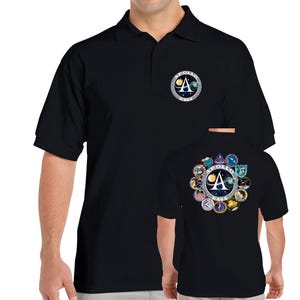 Pode incluir: Camisola polo preta com um patch da missão Apollo da NASA no peito esquerdo. A parte de trás da camisola apresenta um patch maior com o logotipo da missão Apollo e vários patches menores.
