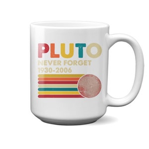 Peut inclure: Mug en céramique blanche avec le mot "PLUTO" en lettres colorées. En dessous, les mots "NEVER FORGET 1930-2006" et un graphique de Pluton. La tasse a une anse blanche et est de taille standard.