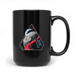 Könnte beinhalten: Schwarze Keramik-Tasse mit einem Weltraum-Design. Das Design zeigt einen stilisierten Mond, die Erde und eine rot-blaue Grafik in einem weißen Dreieck. Die Namen "WISEMAN", "GLOVER", "KOCH" und "HANSEN" sind auf der Tasse aufgedruckt.