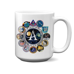 Pode incluir: Caneca de cerâmica branca com um design colorido que apresenta o logotipo do programa Apollo da NASA e os logotipos de cada missão Apollo. A caneca tem uma alça grande.