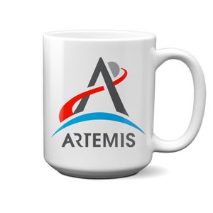 May include: White ceramic mug with a black and red Artemis logo. The logo features a stylized letter A with a red line curving around it and a blue crescent moon. The text "ARTEMIS" is printed below the logo.
