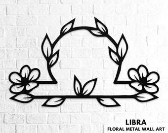 May include: Black metal wall art featuring a floral design with a Libra symbol in the center. The design is reminiscent of a scale with flowers on either side. The text "LIBRA FLORAL METAL WALL ART" is displayed below the design.