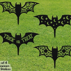 May include: Set of four black metal Halloween yard stakes featuring bats with different designs. One bat has a spiderweb design, one has stars and moons, one says "Trick or Treat", and one has a spiderweb design with stars.