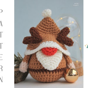 May include: A crocheted reindeer gnome with a brown body, white beard, and red nose. The gnome is wearing a brown hat with a white trim. "Ho ho ho!" is written in green text on a white background.