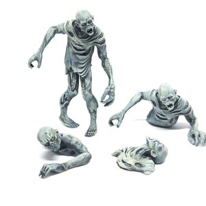 May include: Four gray zombie figurines, one standing, one crawling, and two lying down. The figurines are detailed with realistic features, including exposed bones and rotting flesh.