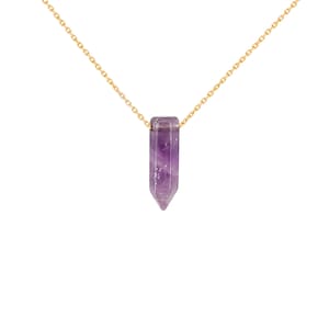 Puede incluir: Un collar de cadena dorada con un colgante de cristal de amatista púrpura en forma de punta.