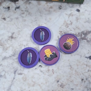 Op de afbeelding: Vier paarse spel fiches met verschillende illustraties. Twee fiches tonen een blauwe veer, &eacute;&eacute;n toont een bundel gouden munten in een zwarte handschoen, en een ander toont een bom met een gele explosie. De fiches zijn cirkelvormig met een paarse rand.