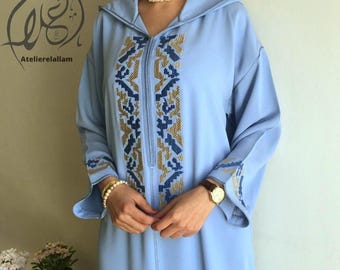 Op de afbeelding: Een lichtblauwe gekapte robe met gouden en blauwe borduursels. De robe heeft een ritssluiting en lange mouwen.