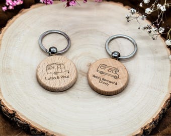 May include: Two round wooden keychains with silver metal rings. The left keychain features an engraved vintage camper trailer and the text Luisa & Paul. The right keychain features an engraved motorhome and the text Petra, Bernard & Charly.