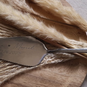 Personalisierter Tortenheber in Silber oder Gold – eine edle und praktische Ergänzung für Hochzeiten, Geburtstage oder Jubiläen. Mit individueller Gravur wird der Tortenheber zu einem besonderen Highlight auf jeder Feier und einem einzigartigen Erinnerungsstück. Ideal als Geschenk zur Hochzeit, Verlobung oder als liebevolles Mitbringsel für Backliebhaber.