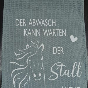 May include: A gray kitchen towel with a white horse design and the text "Der Abwasch kann warten. Der Stall nicht."