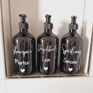 Könnte beinhalten: Drei schwarze Glasflaschen mit Pumpen, beschriftet mit "shampoo Markus", "Duschbad Lian" und "Spülung Simone".