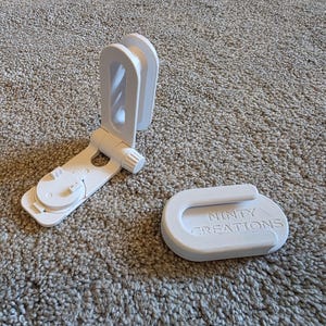 May include: Two white plastic components, one with an adjustable arm and the other with the text "NINTY CREATIONS". The items are on a neutral-colored carpet. The adjustable component has a circular base and a curved top.