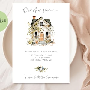Könnte beinhalten: Eine weiße Karte mit dem Text "Our New Home" und einer Aquarellillustration eines Steinhauses mit brauner Tür und schwarzem Dach. Die Karte enthält auch die Adresse und die Namen.