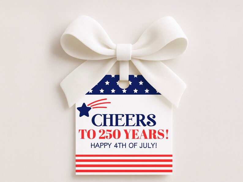 May include: A white gift tag with a blue and white star design and the text "CHEERS TO 250 YEARS! HAPPY 4TH OF JULY!" is attached to a white bow. The tag has a red and white striped bottom and a blue star with red streaks.