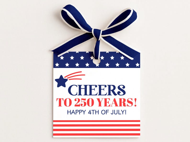 May include: A patriotic gift tag with a blue and white ribbon. The tag features a blue background with white stars, a red and white striped bottom, and the text "Cheers to 250 Years! Happy 4th of July!"