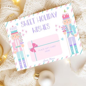 May include: A holiday-themed gift card with the text "Sweet Holiday Wishes." The card features illustrations of nutcrackers in pink and blue, with a pink gift card area. The card is decorated with hearts and stars.