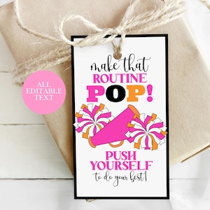 Op de afbeelding: Een cadeaulabel met de tekst "make that ROUTINE POP!" in roze, oranje en zwart. Het label bevat ook een roze megafoon en pompons. De tekst "PUSH YOURSELF to do your best!" is ook opgenomen.