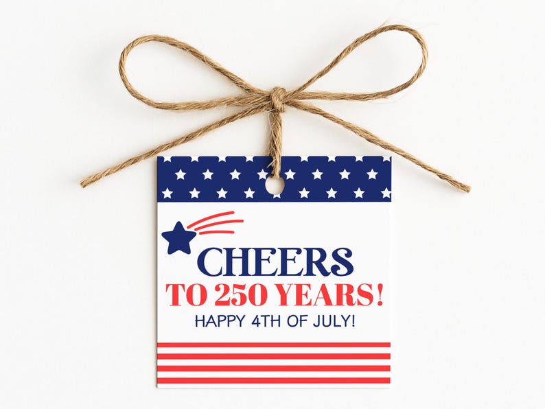 May include: A white gift tag with a blue and red patriotic design, tied with twine. The tag features a blue star with a red comet tail and the text "CHEERS TO 250 YEARS! HAPPY 4TH OF JULY!" in red and blue.