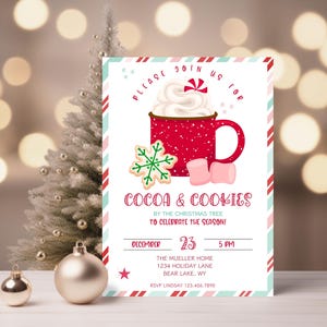 Könnte beinhalten: Eine festliche Einladung zu einer Schokoladen- und Keks-Party am Weihnachtsbaum. Die Einladung zeigt eine rote Tasse mit Schlagsahne und Marshmallows, einen Schneeflocken-Keks und den Text "PLEASE JOIN US FOR COCOA & COOKIES BY THE CHRISTMAS TREE TO CELEBRATE THE SEASON! DECEMBER 23 5 PM THE MUELLER HOME 1234 HOLIDAY LANE BEAR LAKE, WY RSVP LINDSAY 123.456.7810".
