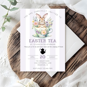 Könnte beinhalten: Eine violett-weiß gestreifte Einladungskarte mit einer Aquarell-Illustration eines Kaninchens, das in einer Teetasse sitzt. Der Text auf der Karte lautet: "Sie sind herzlich eingeladen zum Oster-Tee um 13:00 Uhr. Bitte schließen Sie sich uns für Tee und Oster-Leckereien und die Gesellschaft von Freunden an. April 20 Sonntag. The Hadley Home 1234 Cottontail Lane Mountain, ID RSVP Linley 123.456.7890"