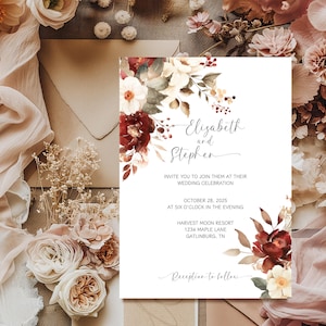 May include: Wedding invitation featuring the names "Elizabeth and Stephen" in elegant script. The invitation includes the date, time, and location of the wedding, surrounded by watercolor floral arrangements in burgundy, cream, and gold.