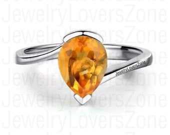 May include: A silver ring with a pear-shaped orange gemstone. The ring has a simple, elegant design and is perfect for everyday wear.