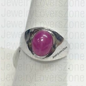 Op de afbeelding: Een zilveren ring met een grote, ovale, dieproze edelsteen. De ring heeft een gladde, gepolijste band en een bezel setting. De achtergrond heeft de tekst "JewelryLoversZone".