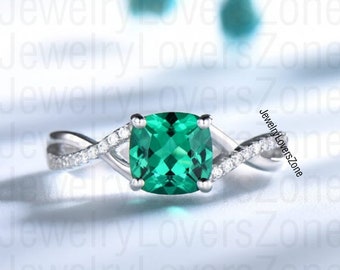 Puede incluir: Un anillo de plata con una banda retorcida y una gran piedra preciosa cuadrada de color verde esmeralda. La banda está adornada con pequeñas piedras transparentes.