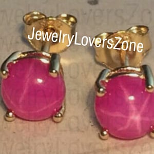 Pode incluir: Um par de brincos de ouro com pedras preciosas de rubi estrela rosa. Os brincos têm um estilo simples e clássico.