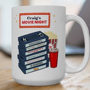 Pode incluir: Caneca de cerâmica branca com um design de noite de cinema vermelho e branco. O design apresenta uma pilha de fitas VHS com títulos de filmes, um balde de pipoca vermelho e branco e um copo vermelho com um canudo. O texto "Craig's Movie Night" está no topo do design.