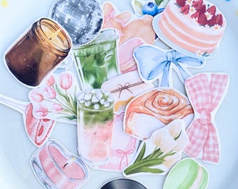 May include: A collection of colorful stickers featuring a variety of designs. Included are a disco ball, a candle, a cake with strawberries, a vinyl record, a macaron, and other food and decorative items.