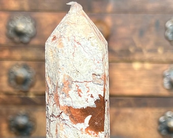 May include: A white and orange crystal point with a rough, textured surface. The crystal has a pointed top and a flat base.