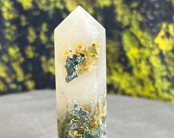 May include: A white agate crystal point with green and yellow inclusions. The crystal is polished and has a smooth, glassy surface.