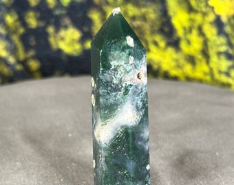 May include: A green and white agate crystal point with a pointed tip and a smooth, polished surface.