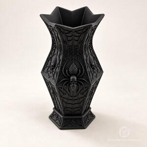 Three-quarter studio view of the Noctara matte-black gothic vase showing its star-shaped rim and raised spiderweb details.