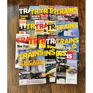 May include: A collection of vintage "Trains" magazines with colorful covers. The magazines feature various articles on railroads, with titles like "Chicago", "Santa Fe Trainmaster", and "Mountain Railroad".