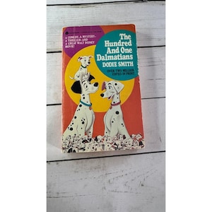 Peut inclure: Livre ancien intitulé "Les 101 Dalmatiens" de Dodie Smith. La couverture présente des illustrations de chiens dalmatiens tachetés de noir, sur un fond rouge et orange. Le texte indique "Plus de deux millions d'exemplaires imprimés".