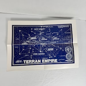 Op de afbeelding: Een gevouwen kaart van het Terran Empire, met een blauw en wit sterrenkaartontwerp. De kaart is gelabeld met kwadrantnamen en de tekst "Kaart van het Tweede Tijdperk". De titel "Terran Empire" is prominent aanwezig.