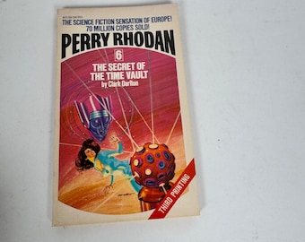 May include: A vintage paperback book titled "Perry Rhodan: The Secret of the Time Vault" by Clark Darlton. The cover features a retro science fiction illustration with a woman in a blue jumpsuit, a futuristic robot, and a red and orange sphere. The book is a third printing.