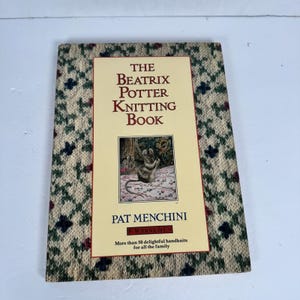 May include: The Beatrix Potter Knitting Book by Pat Menchini. The book cover features a cream-colored background with a pattern of green, blue, and red floral designs. The title is in large, bold letters, and the cover includes an illustration of a mouse.
