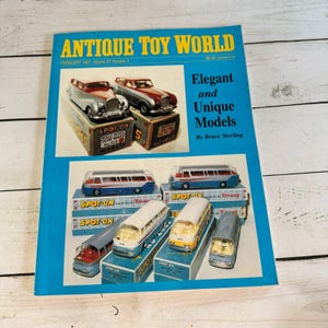 Könnte beinhalten: Antique Toy World Magazin vom Februar 1997, Band 27 Nummer 2. Das leuchtend blaue Cover zeigt Fotografien von alten Spot-On Modellautos und Bussen in ihren Originalverpackungen mit dem Text Elegant and Unique Models by Bruce Sterling.