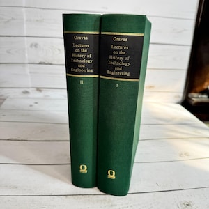 Pode incluir: Dois livros de capa dura verdes. Os livros são intitulados "Oravas Lectures on the History of Technology and Engineering". As lombadas são pretas com letras douradas. O livro da esquerda é rotulado "II" e o da direita "I".