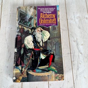 Pode incluir: Um livro de bolso intitulado Alchemy Unlimited de Douglas W. Clark. A capa apresenta uma figura barbuda com um manto preto e branco, leggings vermelhas e sapatos verdes, em pé sobre um pilar de pedra, com uma segunda figura ao fundo.