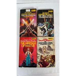 May include: Four vintage paperback books by Marion Zimmer Bradley. Titles include "Two to Conquer", "The Spell Sword", "The Heritage of Hastur", and "The Shattered Chain". Each book features colourful cover art with fantasy themes.