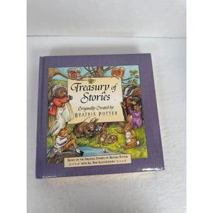 Puede incluir: Un libro de tapa dura titulado "Treasury of Stories" de Beatrix Potter. La portada presenta ilustraciones de animales, incluyendo conejos y ranas, en un estilo colorido y caprichoso. El libro tiene una cubierta morada.