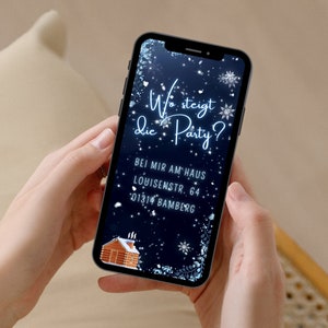 May include: A blue and white smartphone with a winter-themed background. The text on the screen reads "Wo steigt die Party?" with a small gingerbread house illustration. The text below the question reads "Bei mir am Haus Louisenstr. 64 01314 Bamberg".