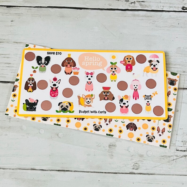 May include: A white card with a yellow border and a brown background. The card has a grid of 18 circles with cute dog illustrations in each circle. The text "Save $70" is in the top left corner. The text "Hello Spring" is in a speech bubble in the top center. The text "Budget with Carly" is in the bottom center.